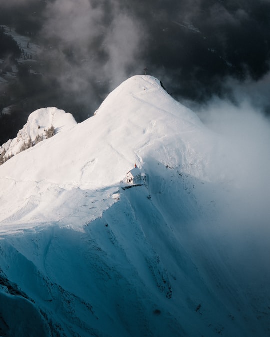 person in white and blue jacket standing on snow covered mountain during daytime in Mount Pilatus Switzerland