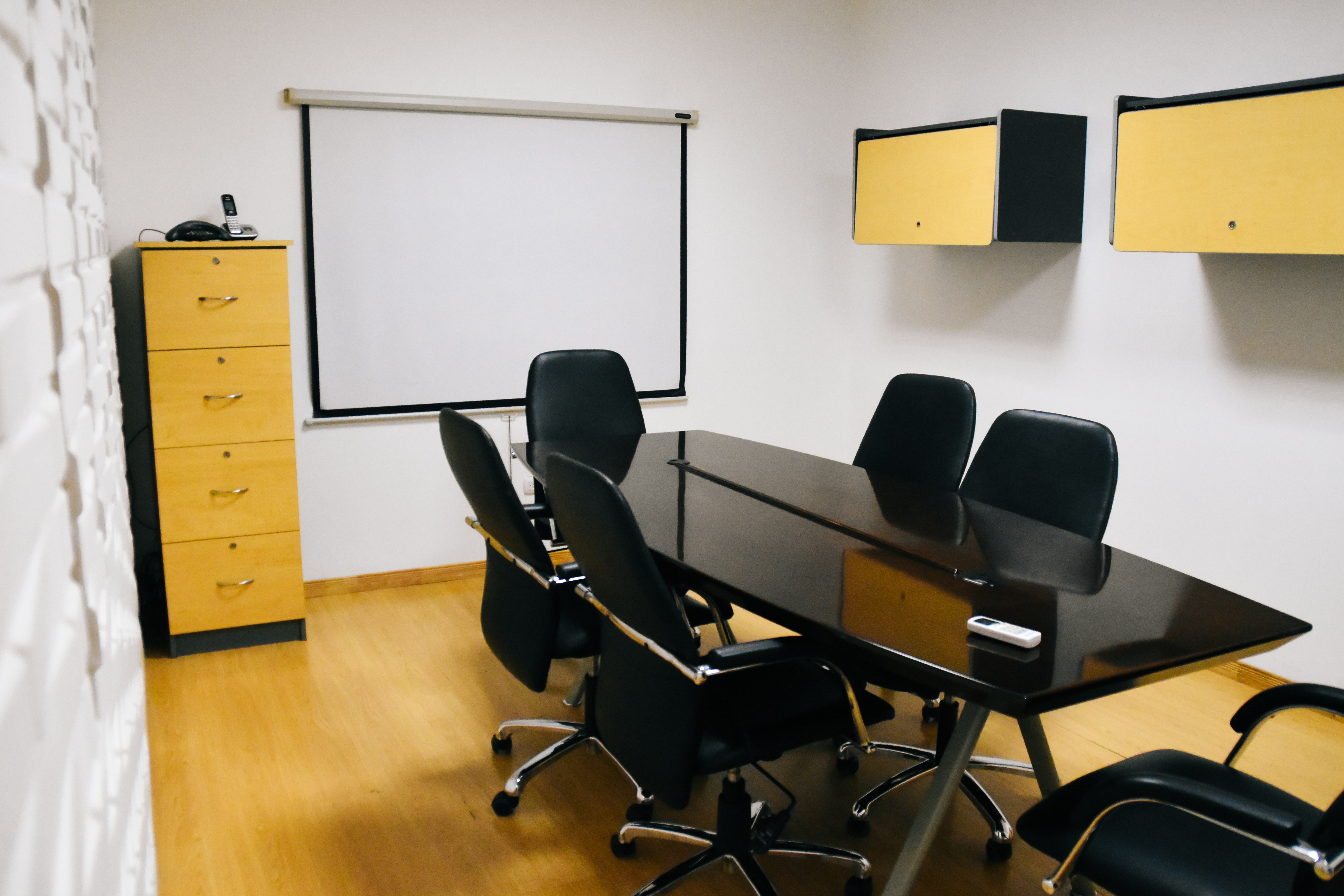Modern dark conference room with large display showing operational maps, dim overhead lighting, professional institutional setting