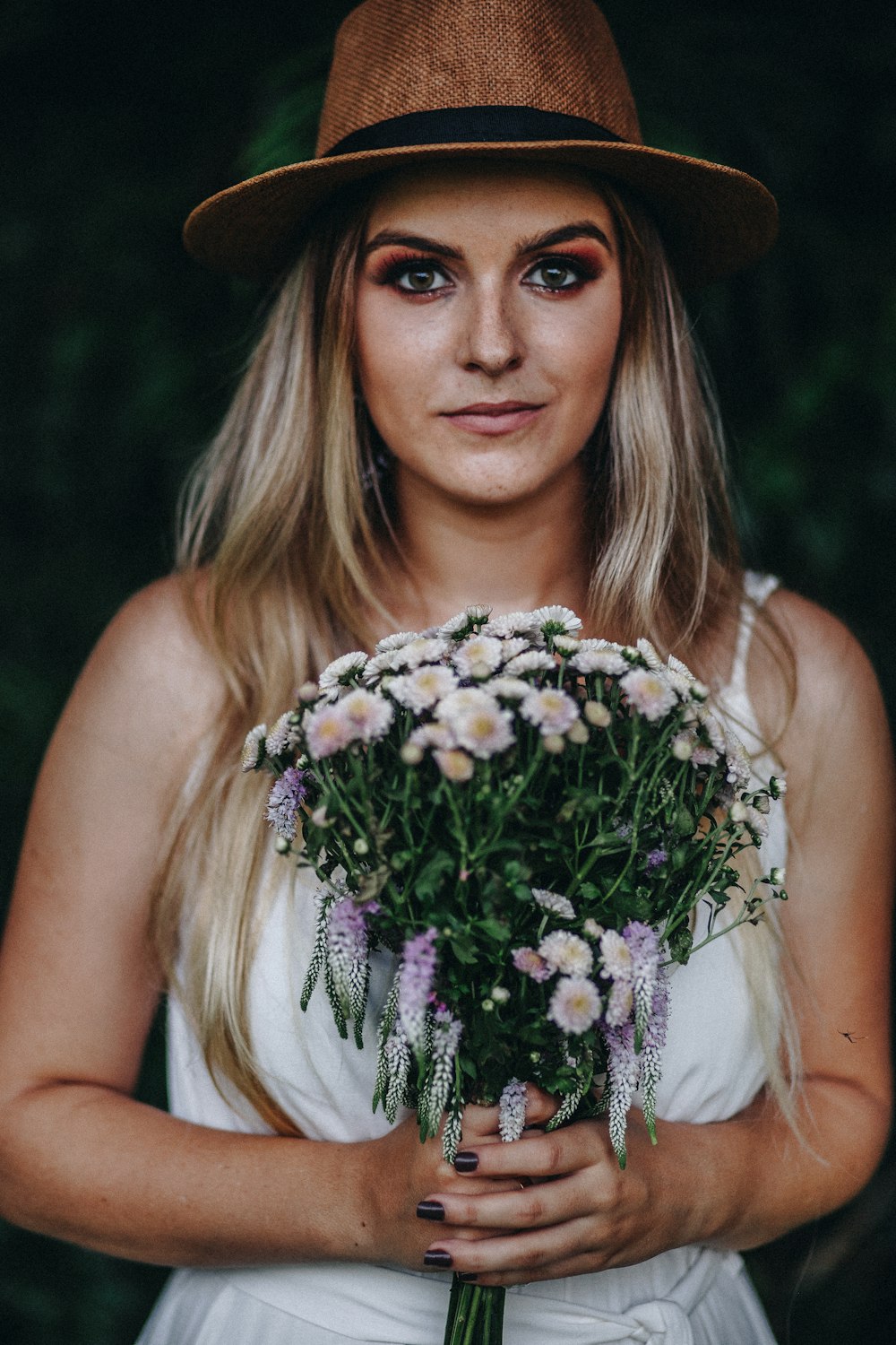 woman in white tank top holding white and pink flowers