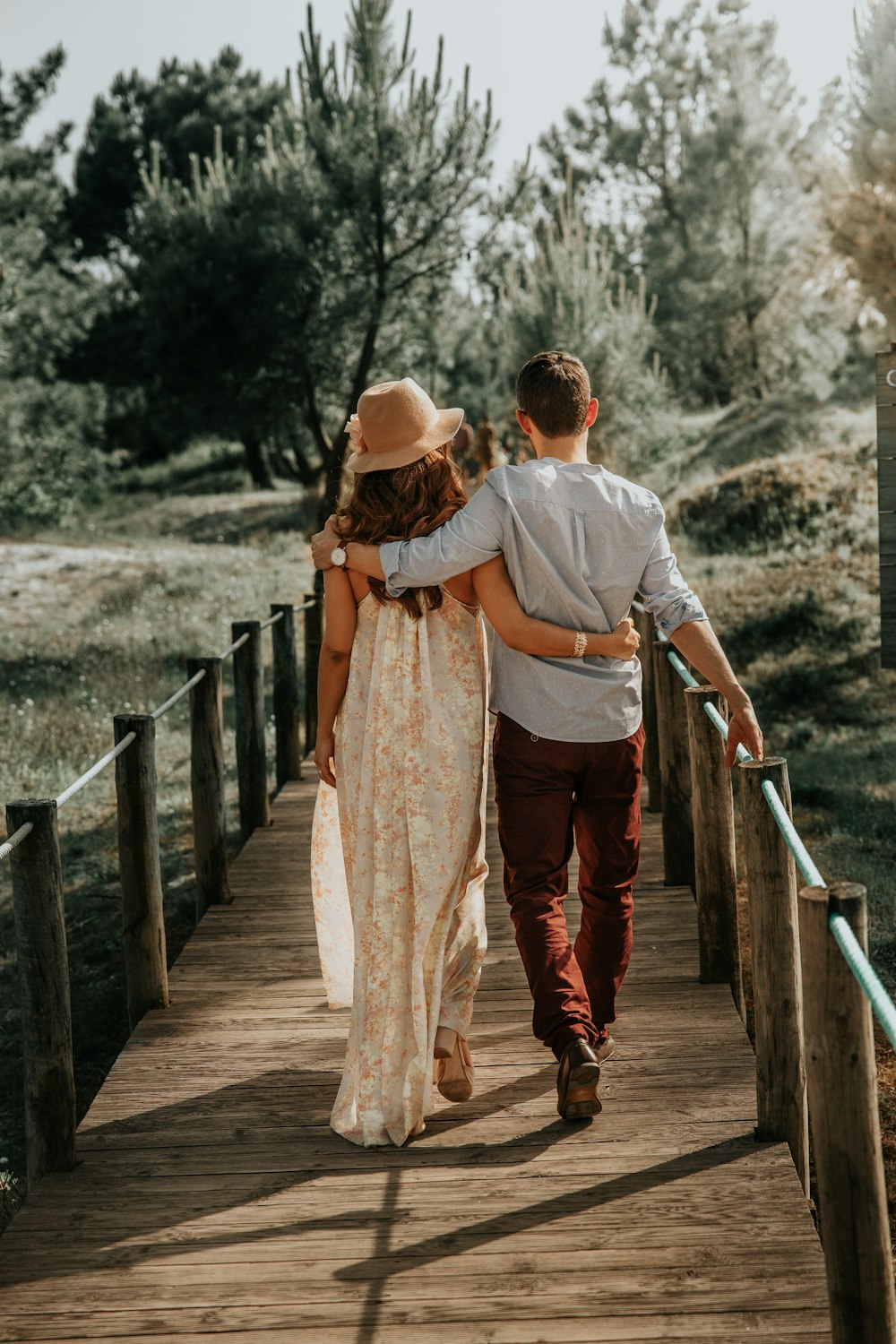 man and woman walking on wooden bridge during daytime