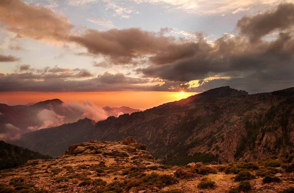 brown mountain under white clouds during sunset