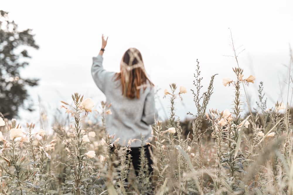 woman in white sweater standing on brown grass field during daytime