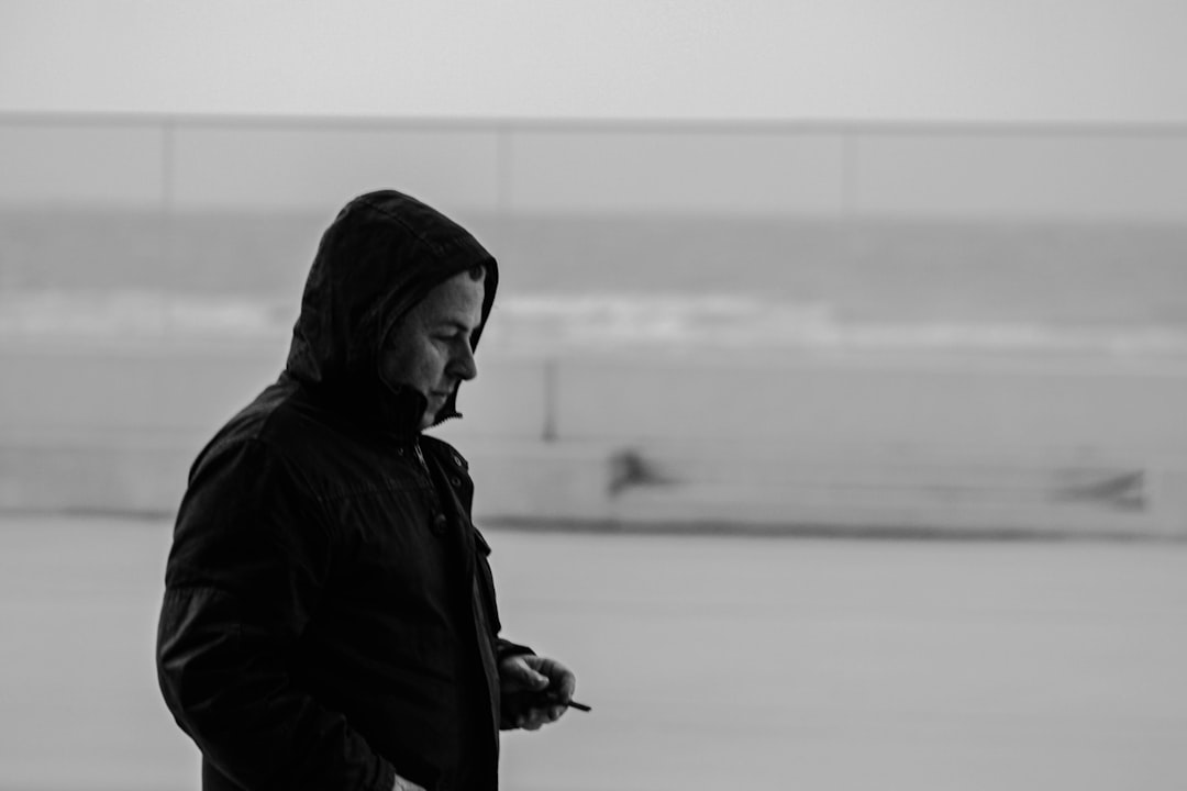man in black hoodie standing near body of water during daytime