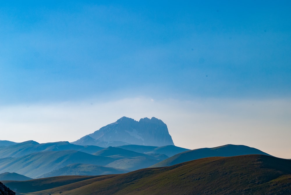 montanhas marrons e brancas sob o céu azul durante o dia