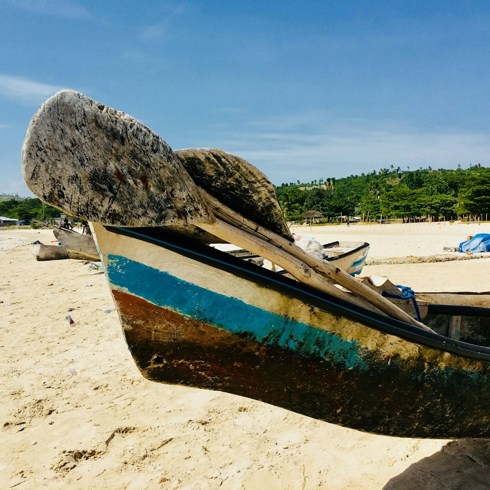 Braunes und blaues Boot tagsüber am Strand