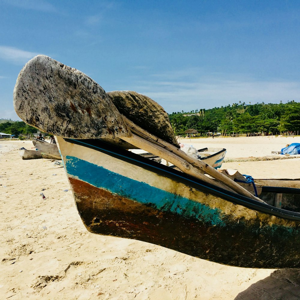 barca marrone e blu sulla spiaggia durante il giorno
