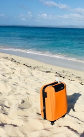 orange and white luggage bag on beach