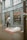 A person is using an ATM outside a building with the logo LCL on it. On the sidewalk, there is a mattress with some cardboard and bedding, suggesting a makeshift sleeping area. Reflections can be seen in the large windows of the building.