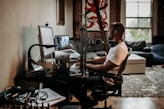 man in white t-shirt sitting on black office rolling chair