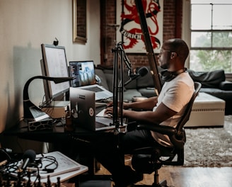 man in white t-shirt sitting on black office rolling chair