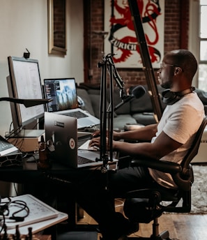 man in white t-shirt sitting on black office rolling chair