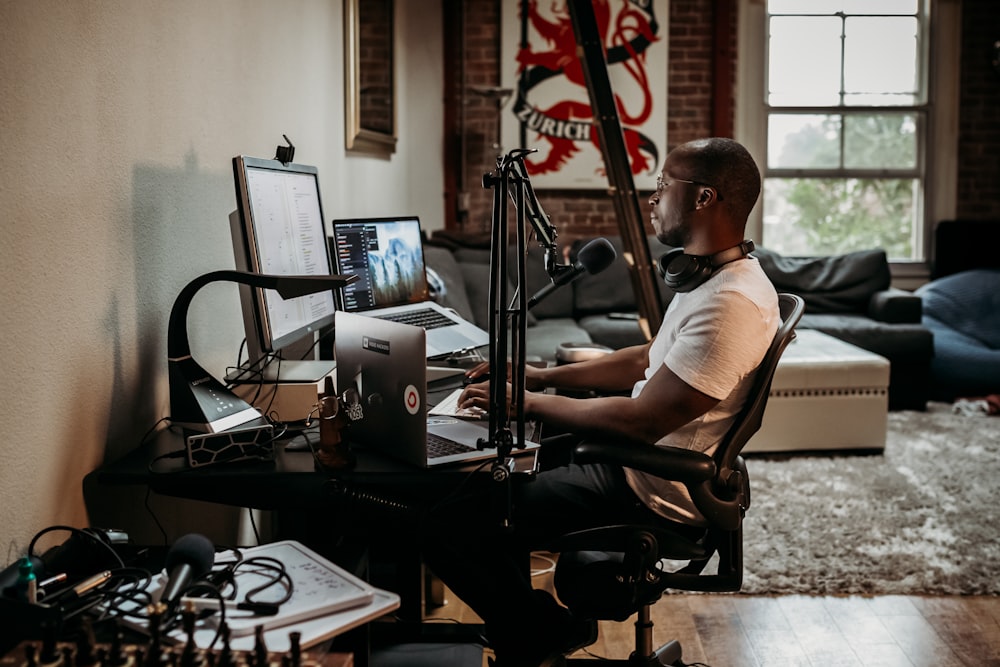 homme en t-shirt blanc assis sur une chaise roulante de bureau noire