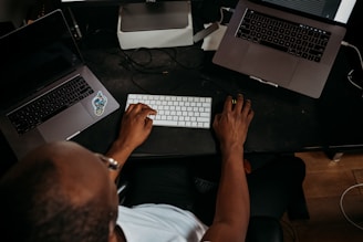 A focused IT specialist working on a laptop surrounded by tech gadgets and notes.
