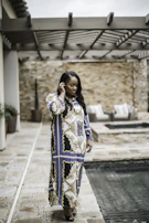 Model in a soft beige resort dress walking along a tropical poolside