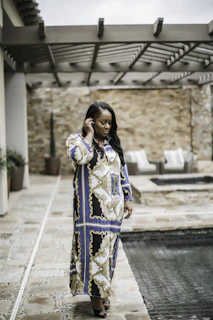 Model in a soft beige resort dress walking along a tropical poolside