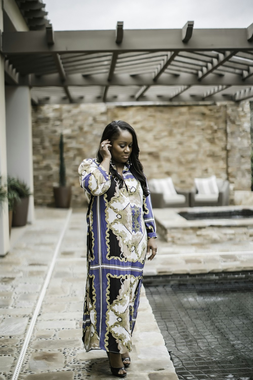 woman in white and blue floral long sleeve dress standing on gray concrete floor during daytime