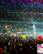 A vibrant crowd dancing under colorful lights at a festival.