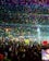 A joyful crowd dancing at a vibrant music festival under colorful lights.