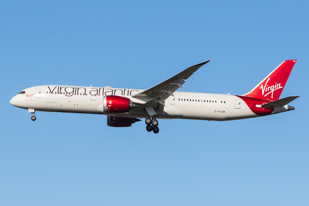 white and red air plane in mid air during daytime