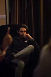 man in black jacket sitting on couch