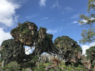 An alien spacecraft hovering above lush forests during the day.