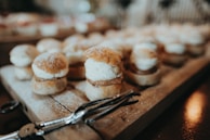 Banana cream-filled brioches arranged neatly on a rustic wooden board.