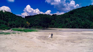 A sunlit wedding aisle adorned with soft sand and terracotta floral arrangements, couples exchanging vows with joyful smiles.