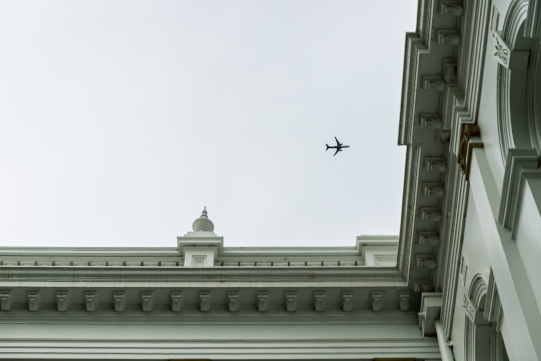 airplane flying over white concrete building