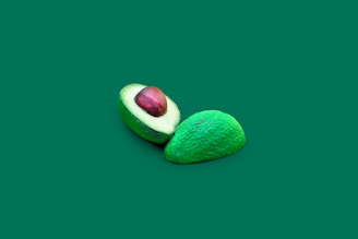 A fresh green avocado sliced in half on a white background, symbolizing healthy keto fats.