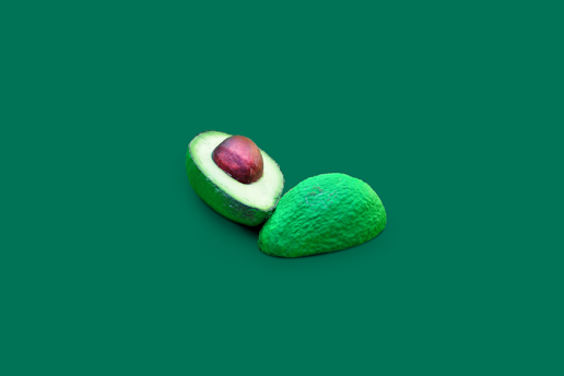 A fresh green avocado sliced in half on a white background, symbolizing healthy keto fats.