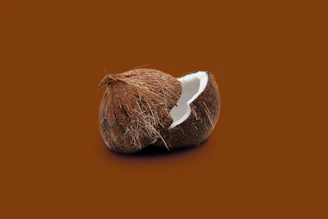 Close-up of a mature brown coconut without husk on a rich brown background highlighting its texture.