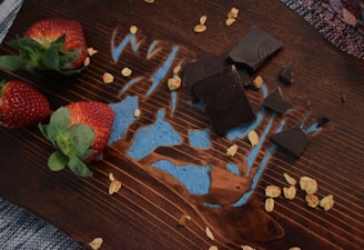 Close-up of fresh strawberries dipped in rich chocolate, arranged on a rustic wooden board.