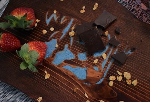 Close-up of fresh strawberries dipped in rich chocolate, arranged on a rustic wooden board.