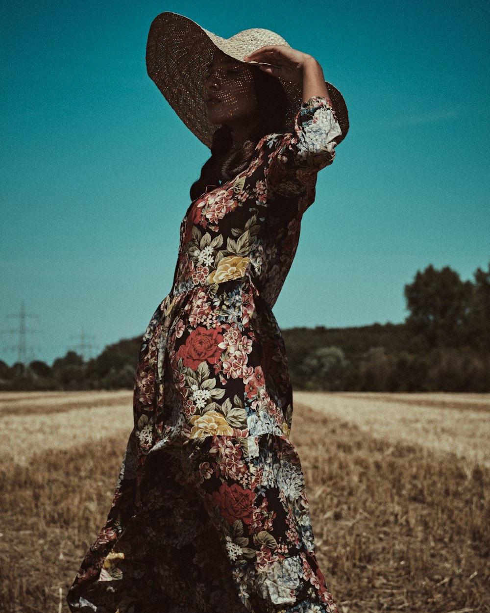 woman in white red and black floral dress standing on brown grass field during daytime