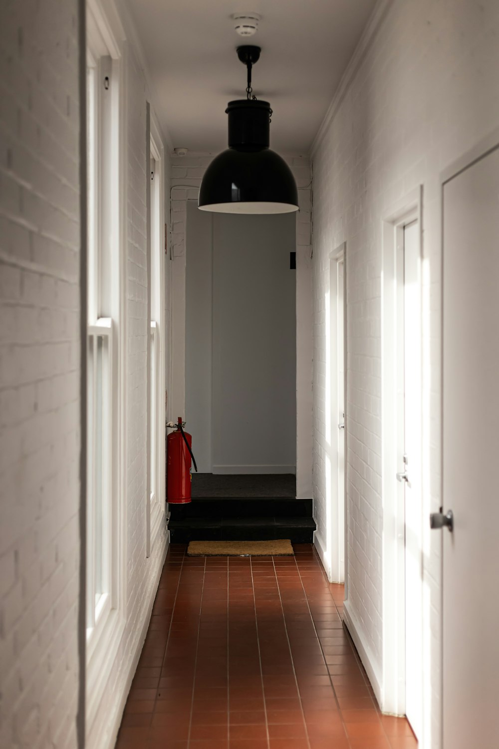 white wooden door near red and black trash bin