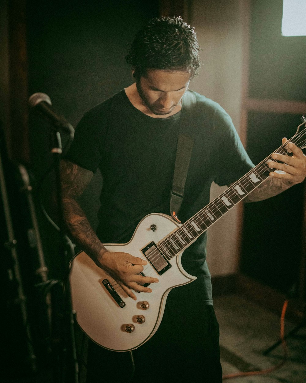 man in black crew neck t-shirt playing white electric guitar