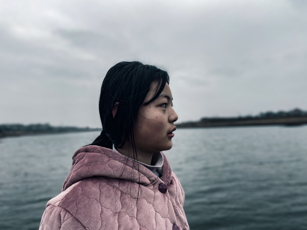 woman in pink and white plaid shirt standing near body of water during daytime