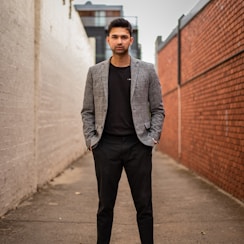 man in gray suit jacket and black pants standing on brown concrete pathway during daytime