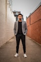 man in gray suit jacket and black pants standing on brown concrete pathway during daytime
