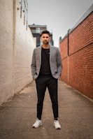 man in gray suit jacket and black pants standing on brown concrete pathway during daytime