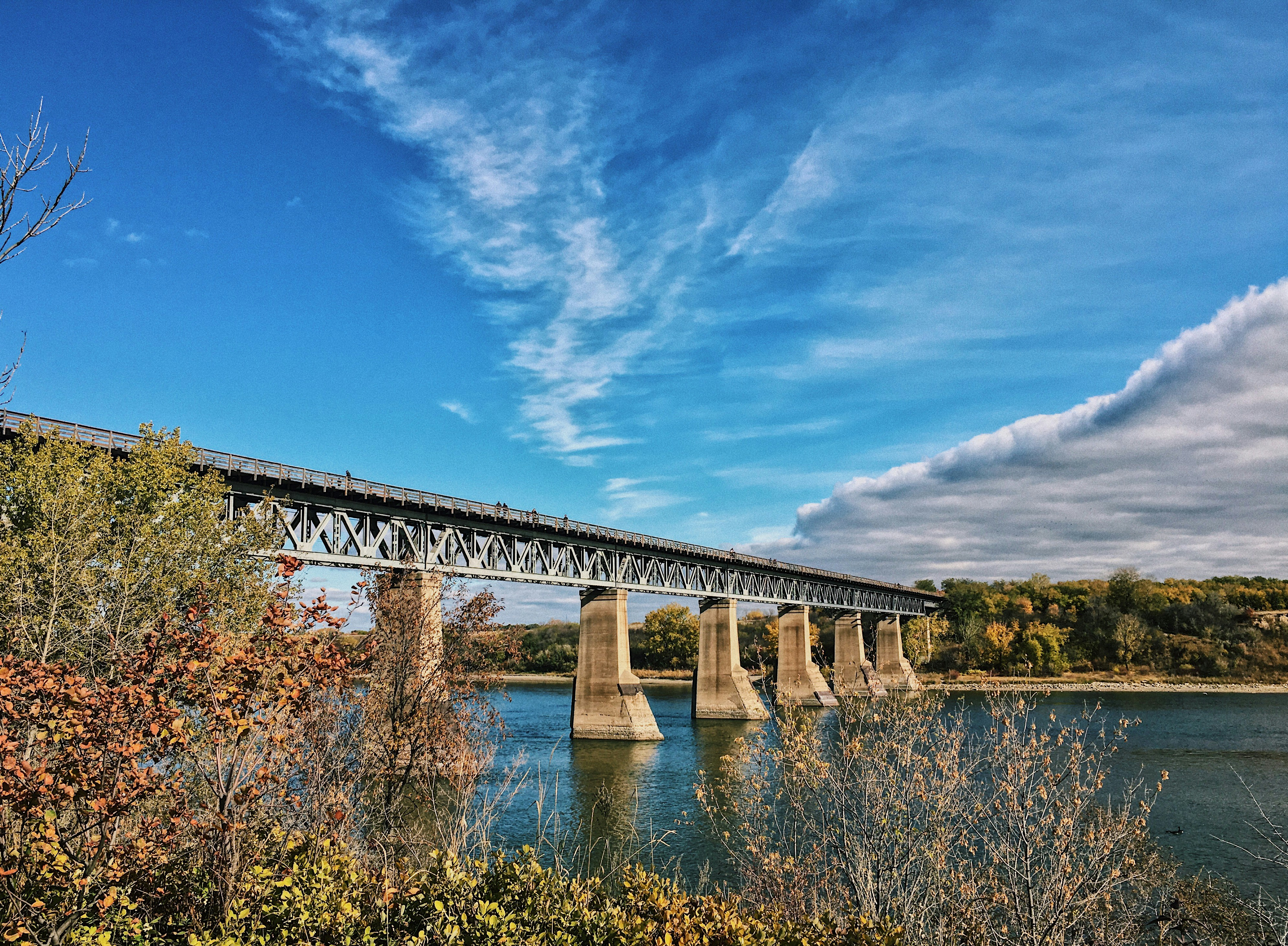 gray concrete bridge over river under blue sky during daytime