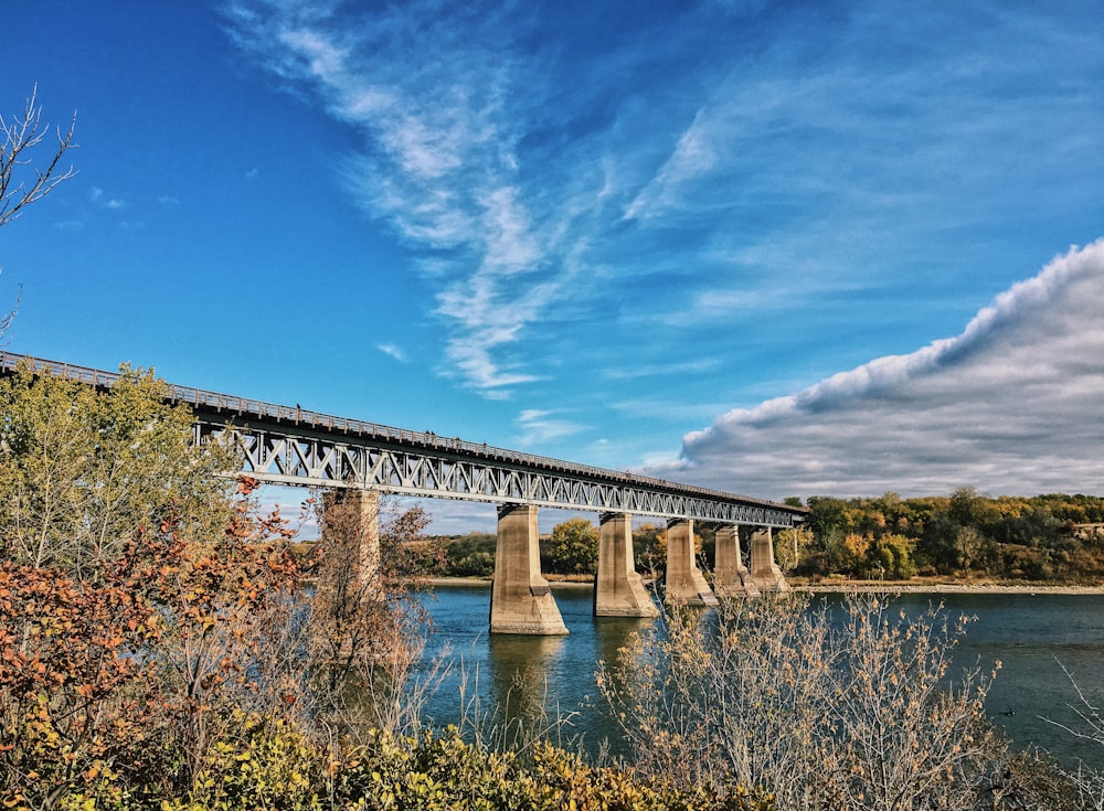 Graue Betonbrücke über den Fluss unter blauem Himmel tagsüber