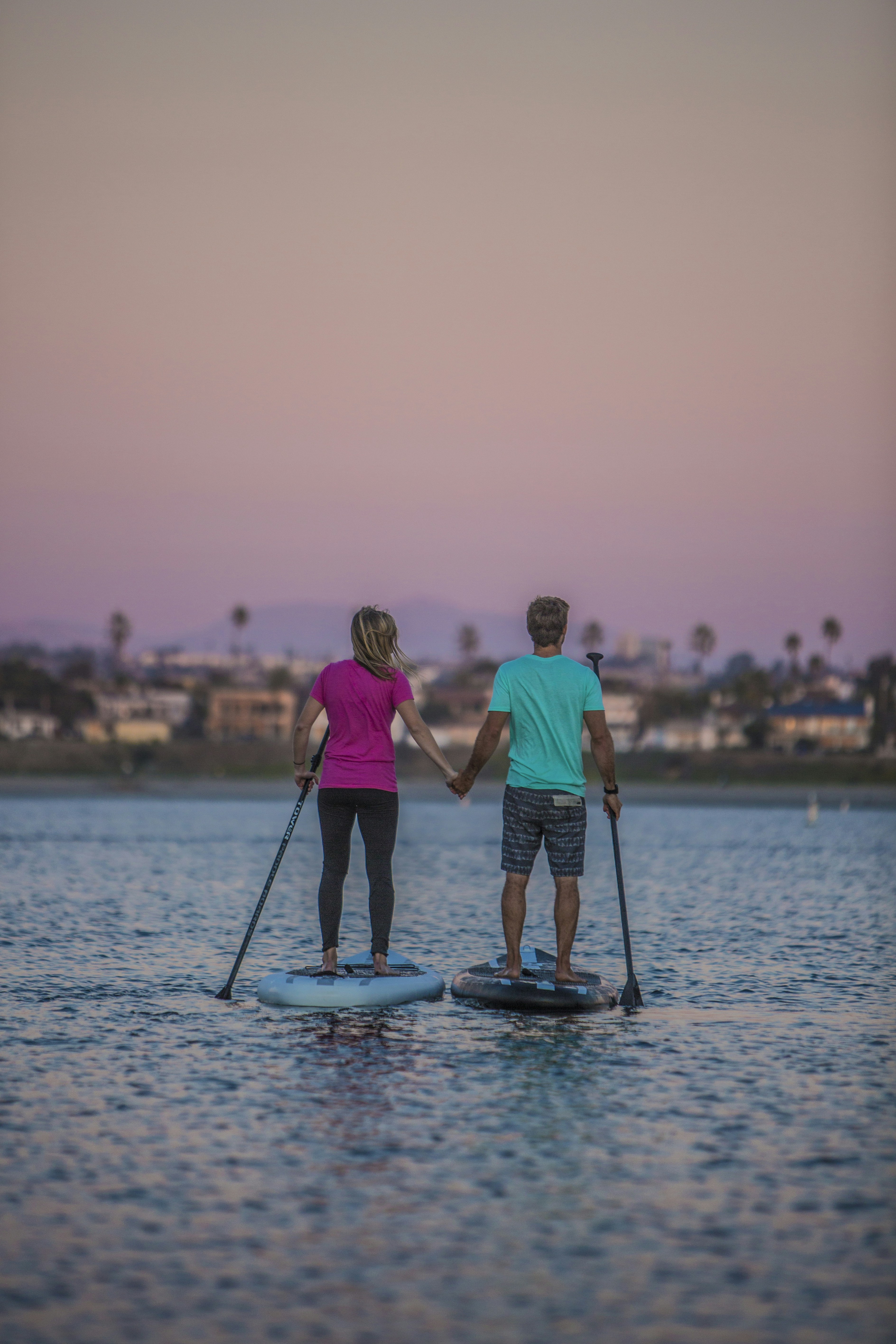 Couple riding on Tower paddle boards during the sunset.