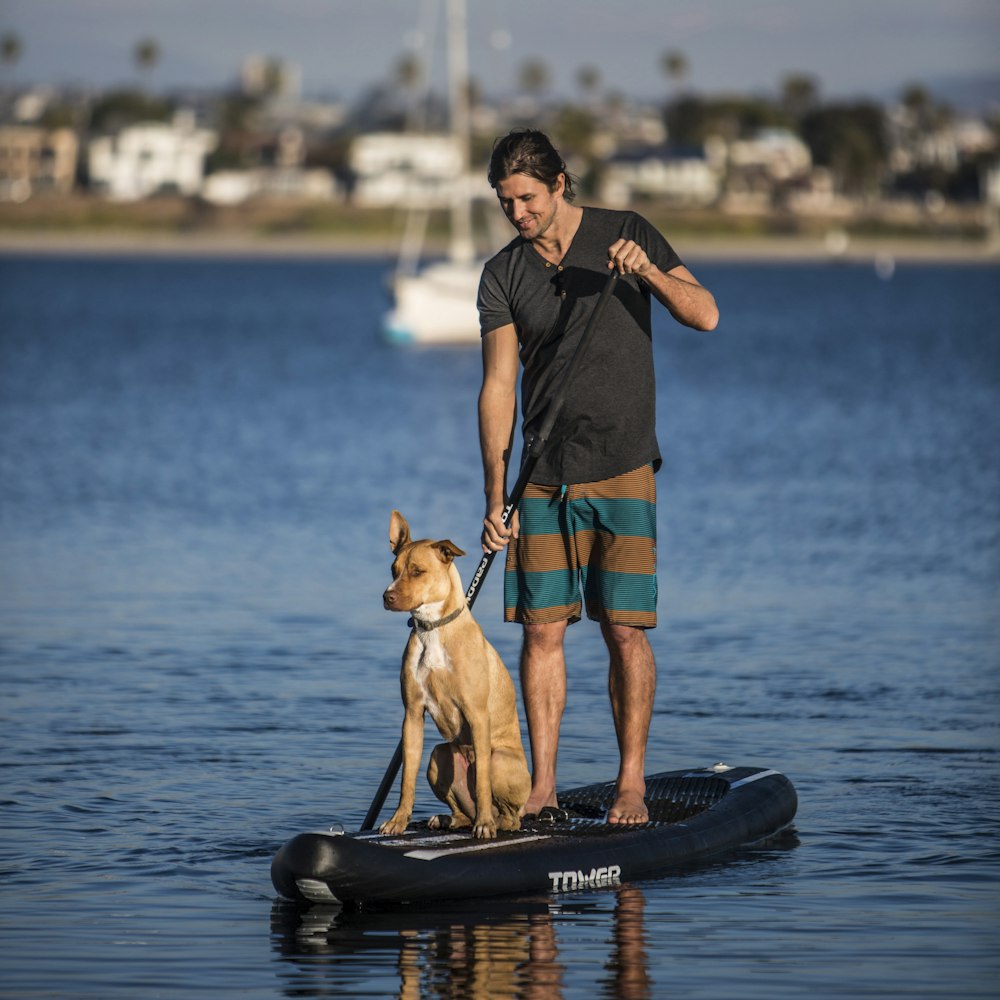 man in blue tank top and blue shorts holding brown short coated dog on black and