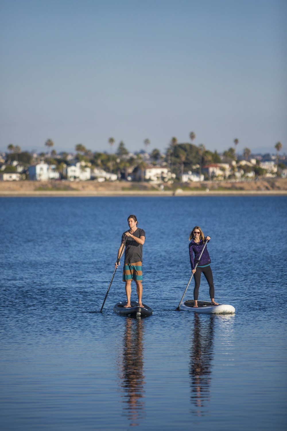 man and woman in blue and black wetsuit riding white and blue kayak on sea during