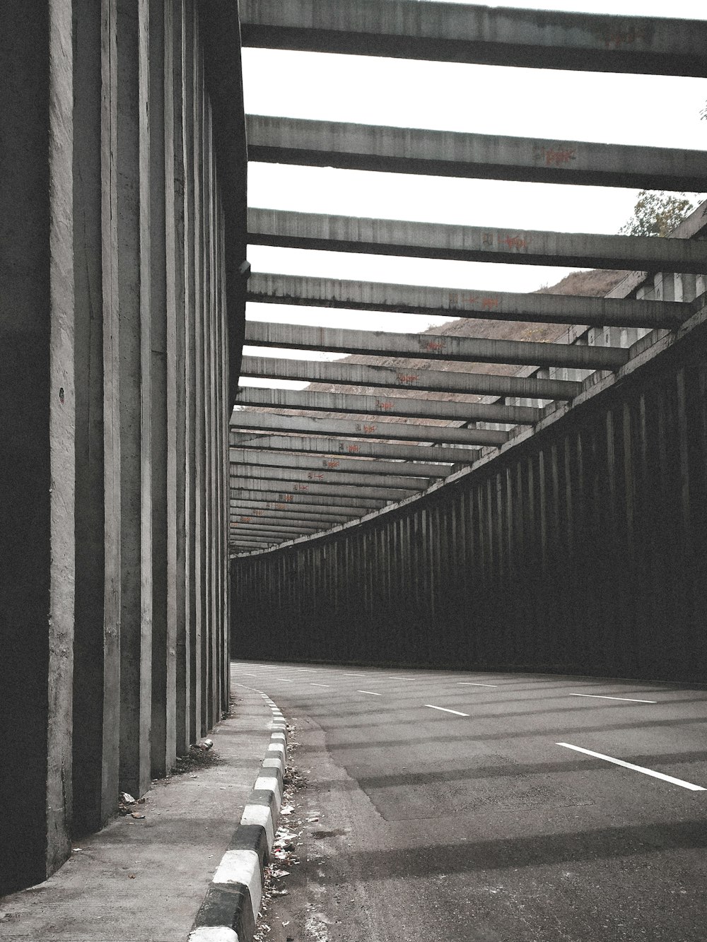brown wooden pathway in between gray concrete walls