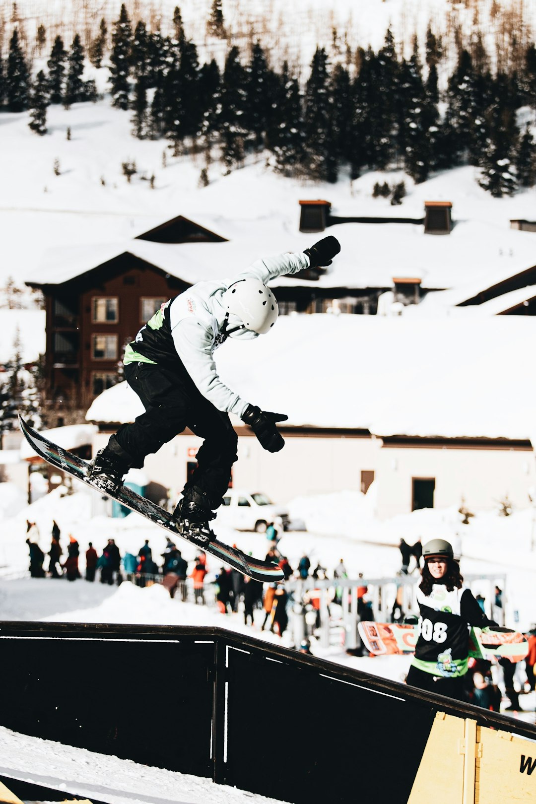 man in white jacket and black pants riding on black and white snowboard during daytime