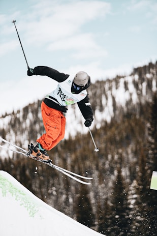 person in orange jacket and black pants riding ski blades on snow covered ground during daytime