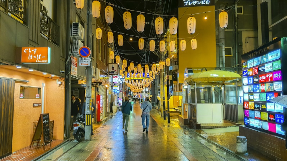 man in blue denim jeans walking on sidewalk during night time