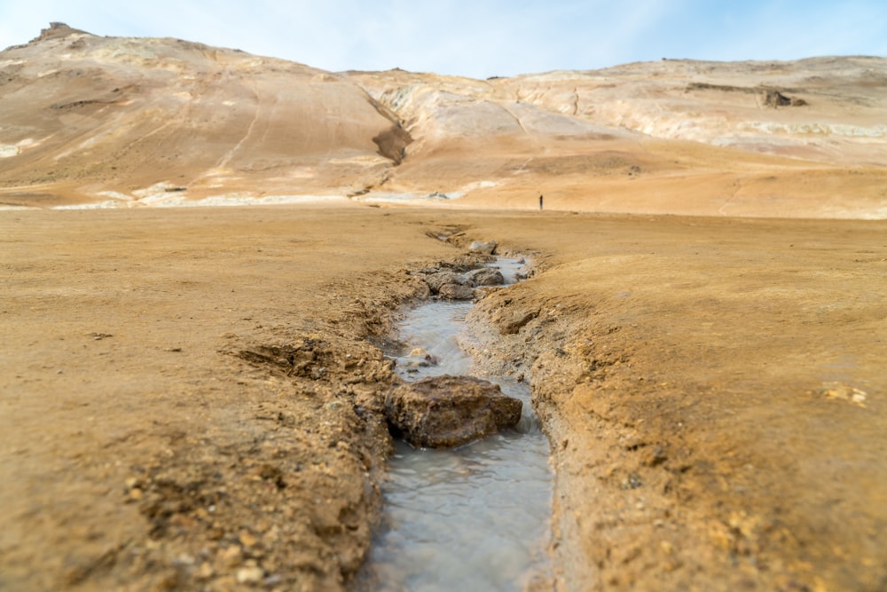 Montañas marrones y grises junto al río durante el día